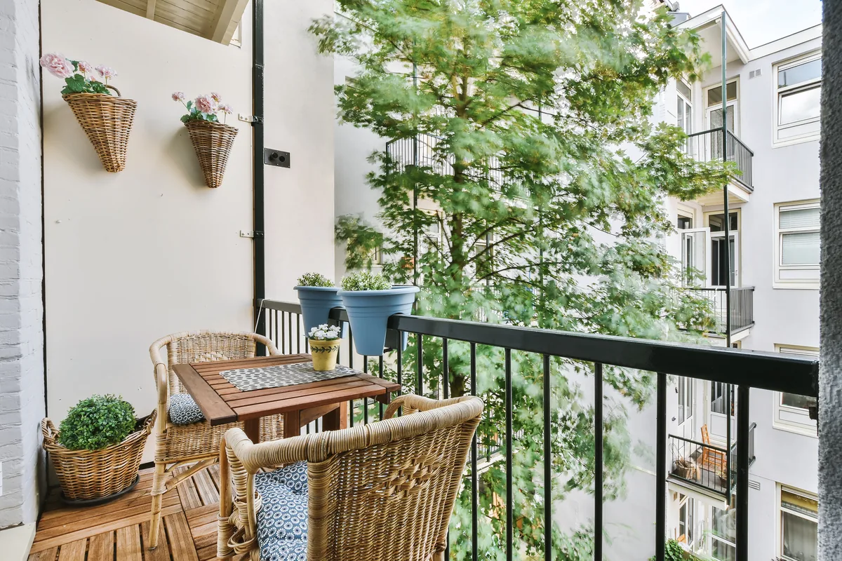 Balcony with wall-hung basket planters and a wooden cafe table