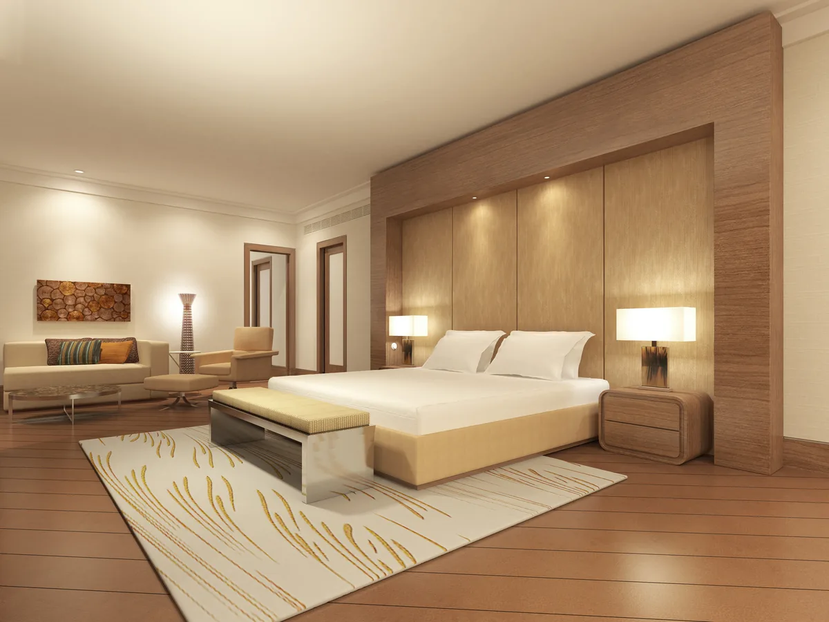 Bedroom with a wood-panelled headboard wall, seating area and patterned rug