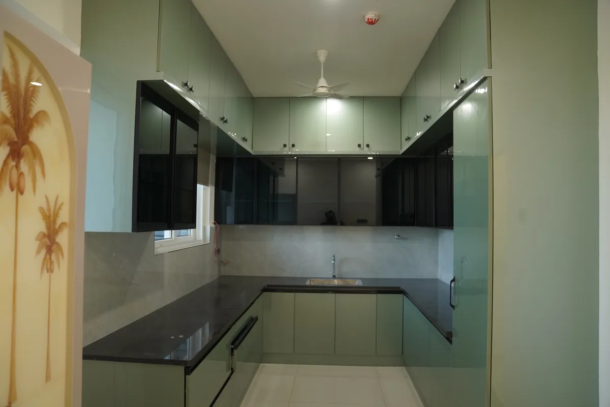 U-shaped sage green kitchen with black glass wall cabinets and granite counter