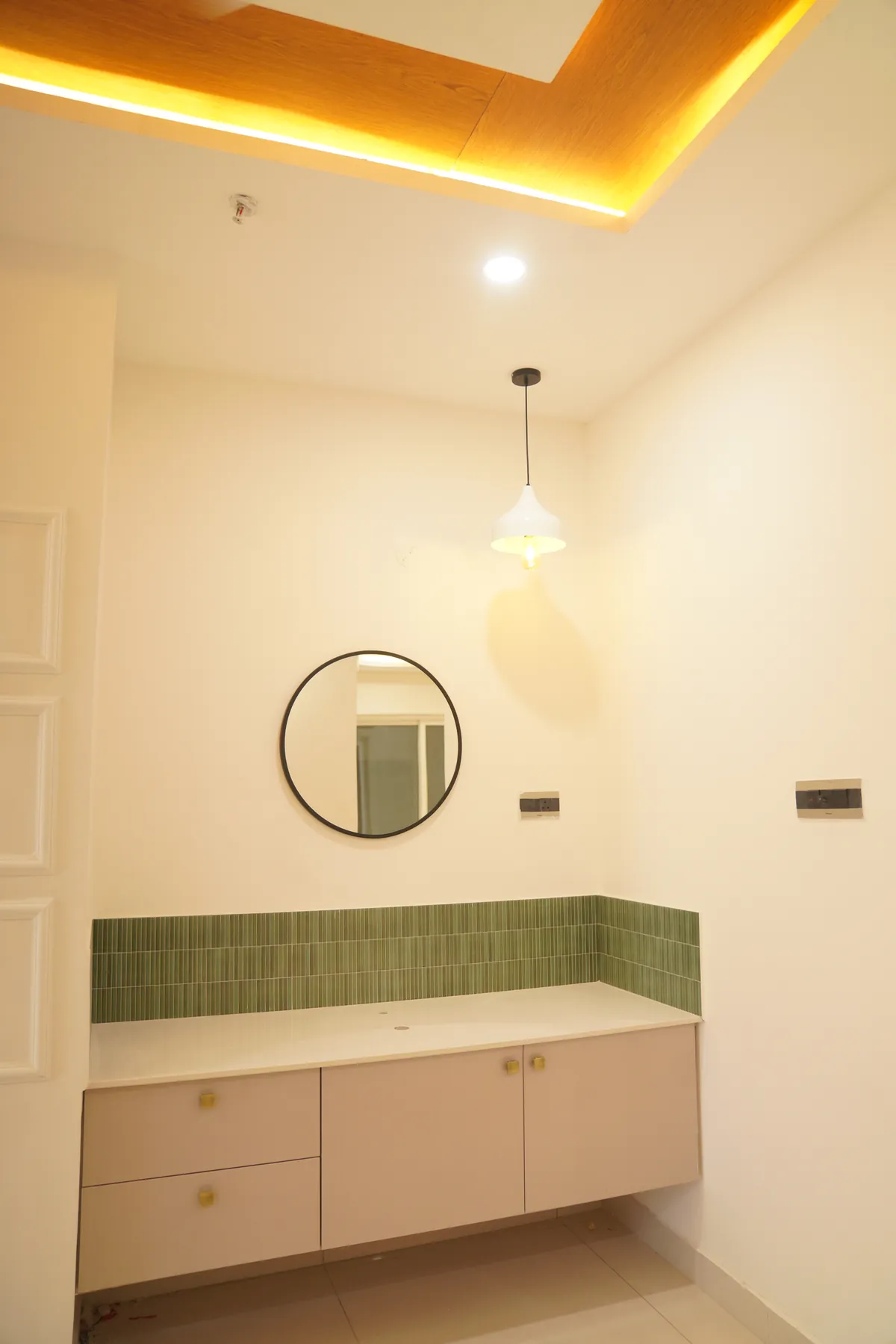Floating vanity with green tile splash, round mirror and pendant light