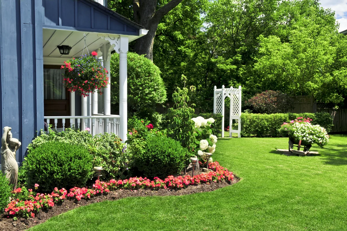 Garden with a white porch, flower beds and lawn