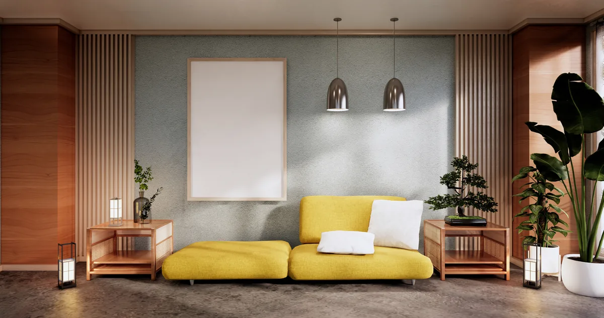 Low yellow sofa against a grey wall with wooden slat panels, pendant lights and indoor plants.