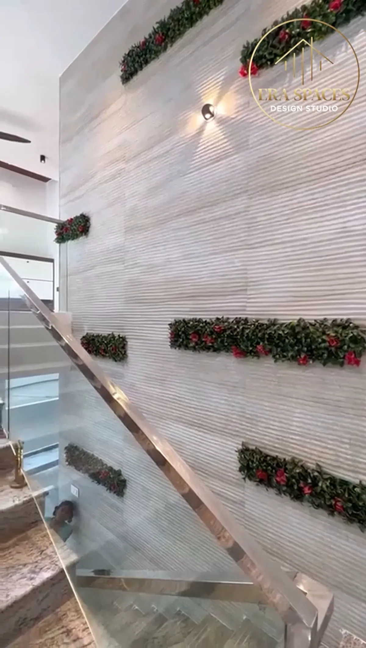 Staircase beside a ribbed stone feature wall with planted green strips and a glass balustrade